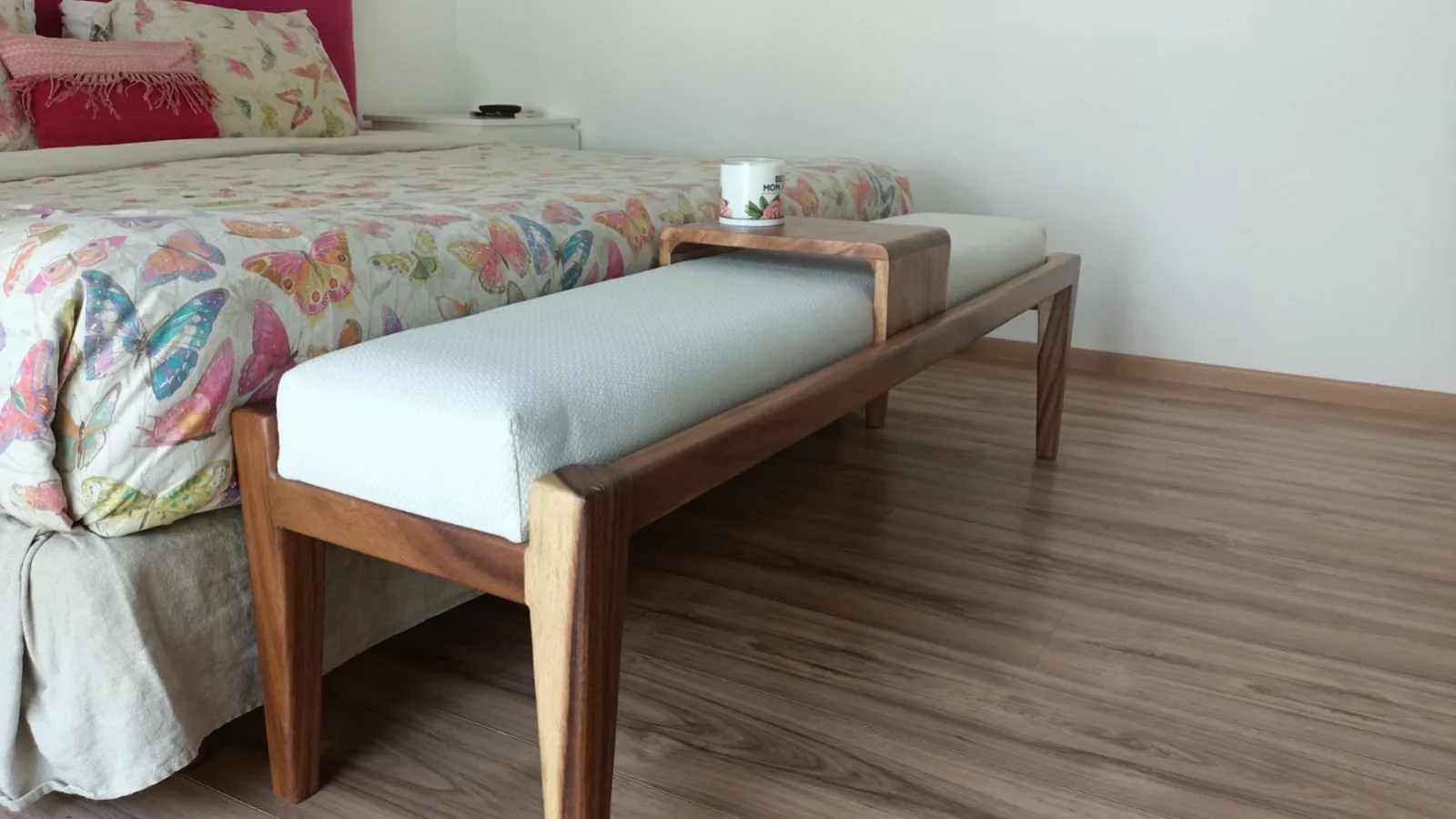 Banca de madera tapizada al pie de cama